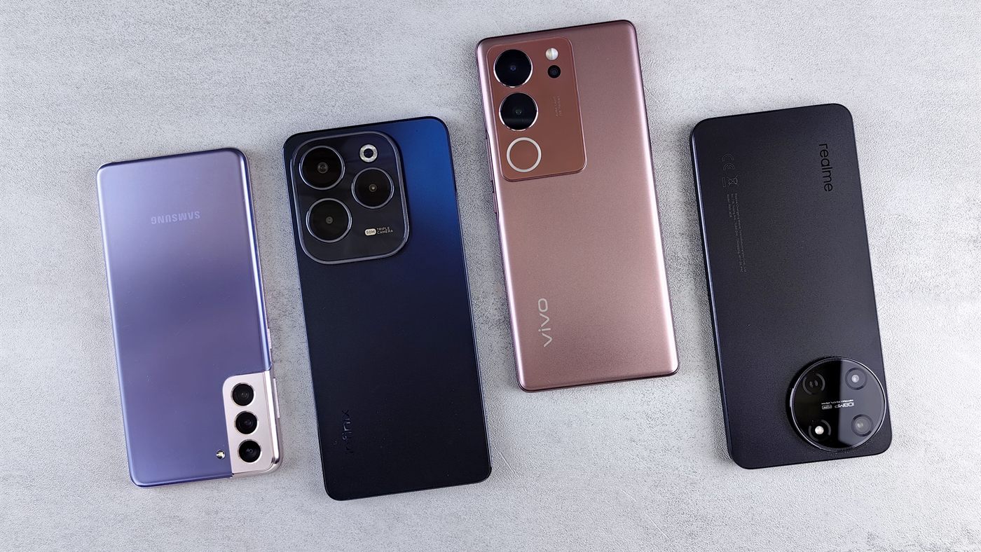 Four Android phones from different brands lying side by side on a grey surface