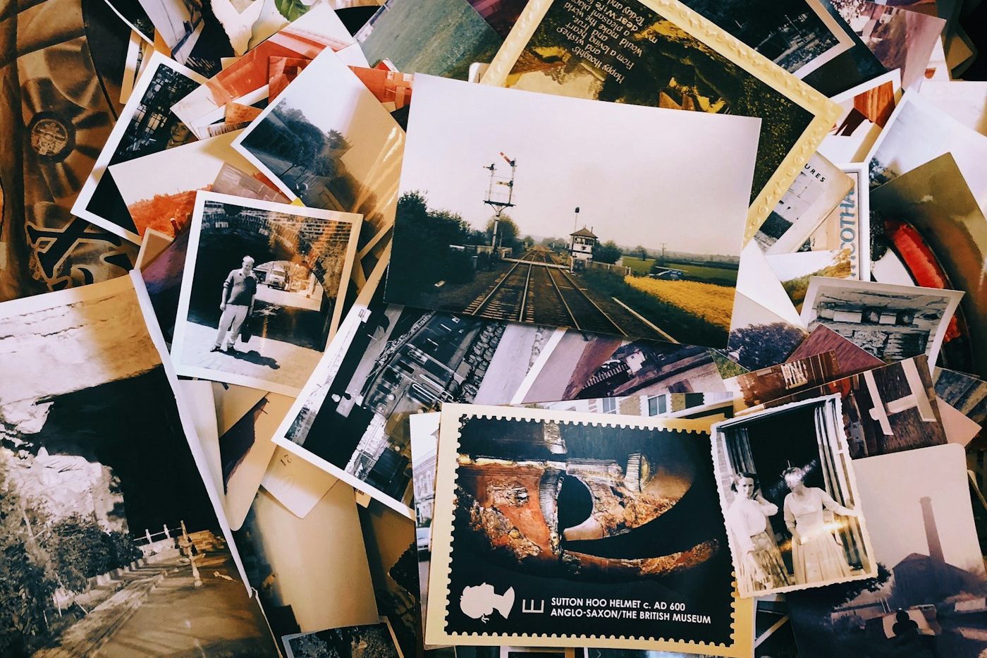 A messy pile of old printed photographs and postcards from many different years