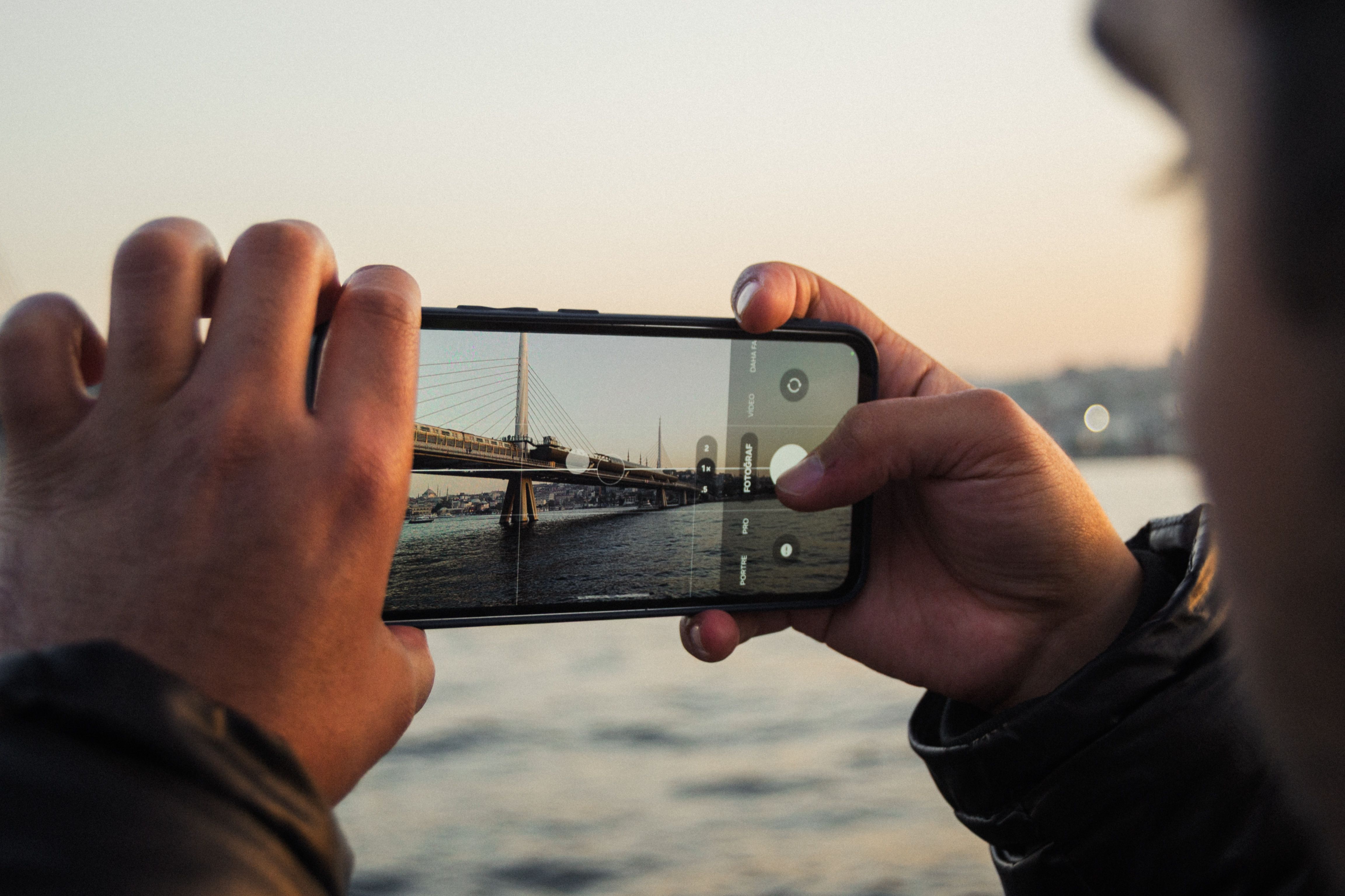 Person photographing a bridge with their phone