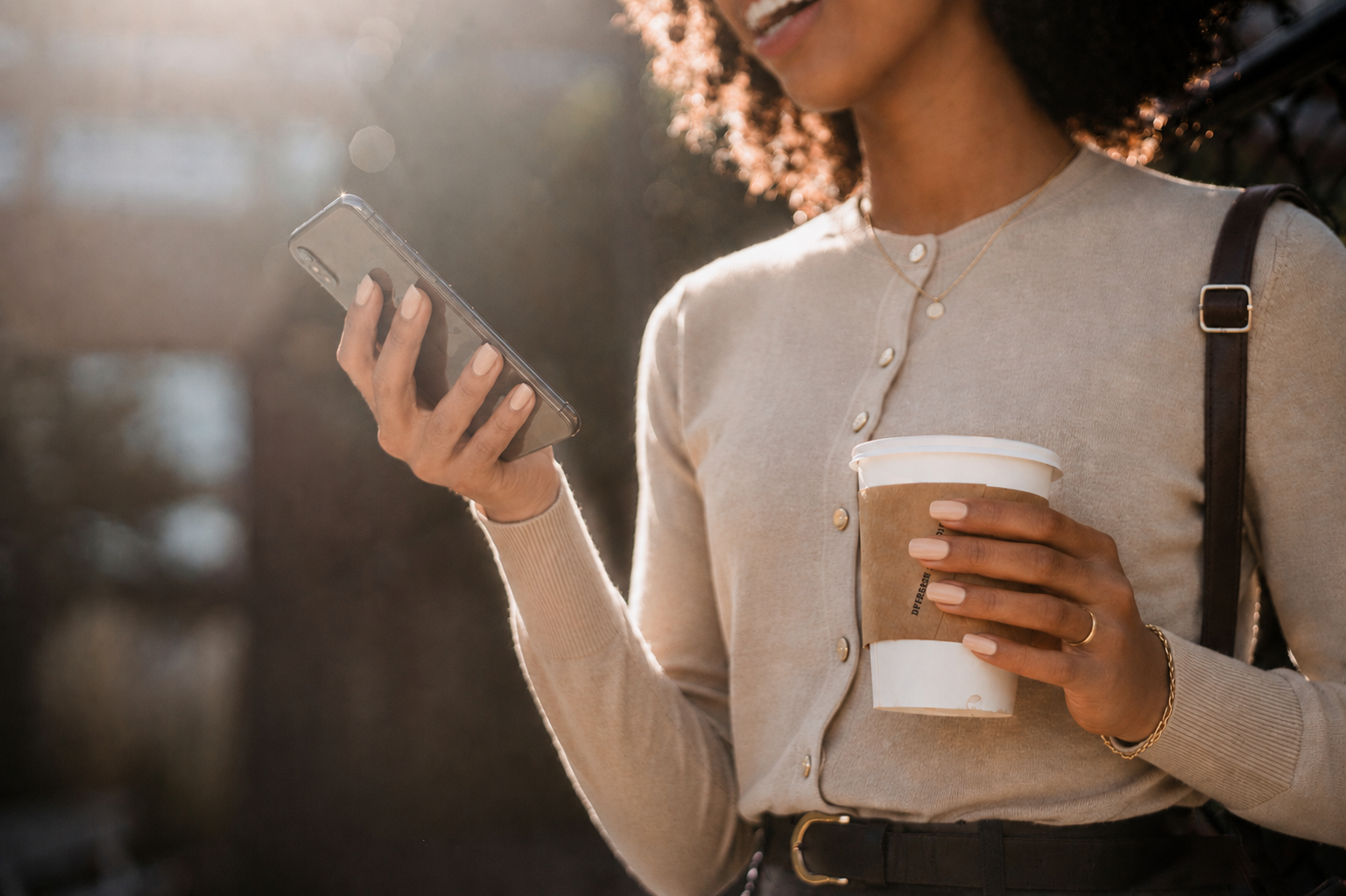 Woman holding a cup while browsing photos on her phone